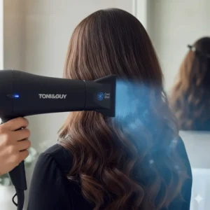 Hand pressing the cool shot button on a hairdryer to set a hairstyle and add shine to thick hair cuticles.