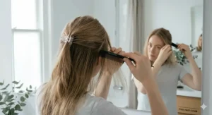 Back view of a woman sectioning fine hair with a clip and a fine-tooth comb to prepare for a professional-style blow-dry.