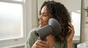A person using the scrunching technique with a curl enhancing hair dryer diffuser to achieve bouncy, frizz-free curls.