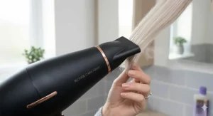 A slim concentrator nozzle attachment for a hairdryer, used for precise styling and smoothing blonde fringes.