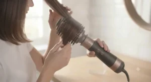 Side profile of a person using the volumising hot air brush to lift and style a section of hair at the roots.
