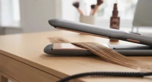 Detailed view of the ultra-smooth, rose-gold ceramic plates of the ionic straightener gliding effortlessly through a section of fine, glossy hair.