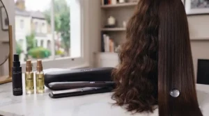 Bottle of professional heat protectant spray next to premium hair straighteners.