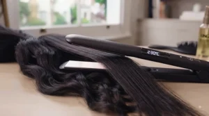 Hairdresser sectioning thick, wavy dark hair with sectioning clips before heat styling.