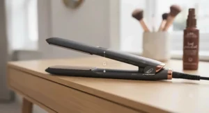 The charcoal grey and copper ionic straightener resting on the light oak vanity, highlighting its slim, ergonomic, and lightweight design suitable for daily use.